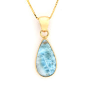 Gold necklace with a teardrop-shaped larimar pendant on a white background