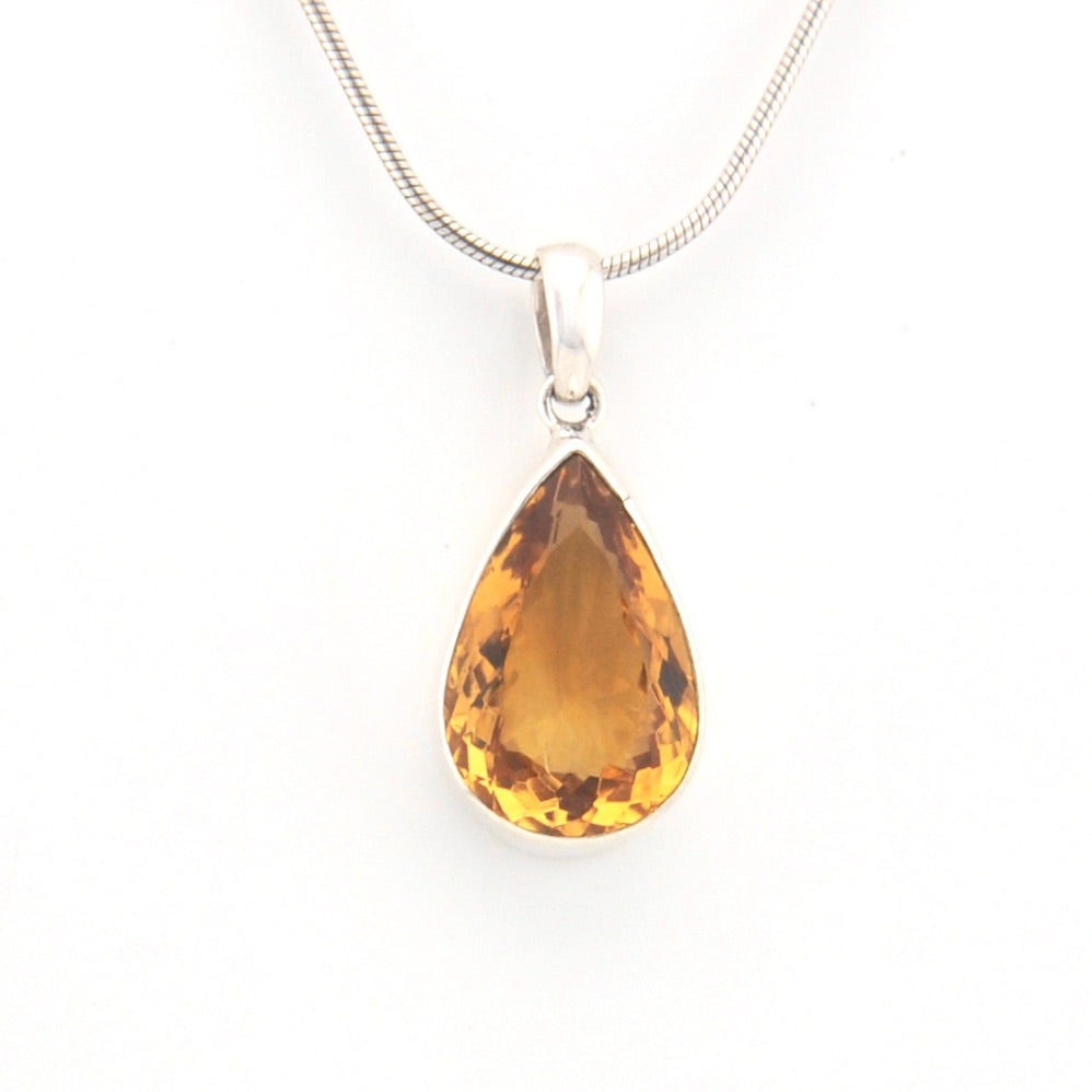 Teardrop-shaped citrine pendant on a silver chain against a white background