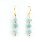 Pair of earrings with light blue beads and gold hooks on a white background
