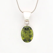 Green gemstone pendant on a silver chain against a white background