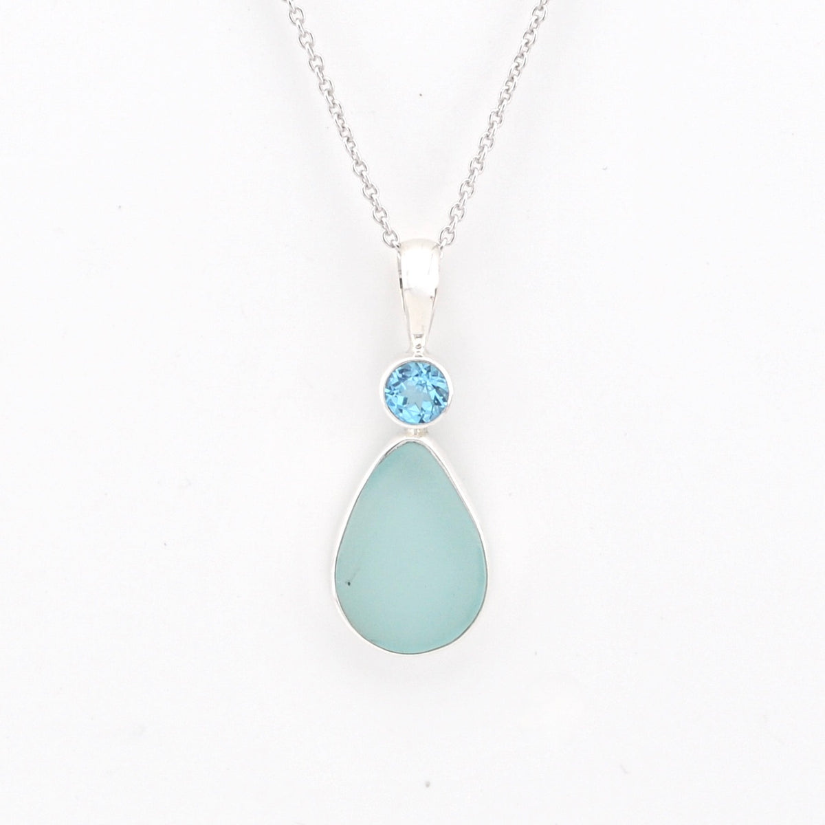 Teardrop-shaped light blue pendant with a blue gemstone on a white background