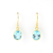 Gold earrings with blue gemstones on a white background