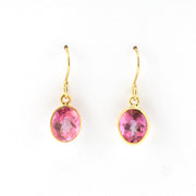 Gold earrings with pink gemstones on a white background