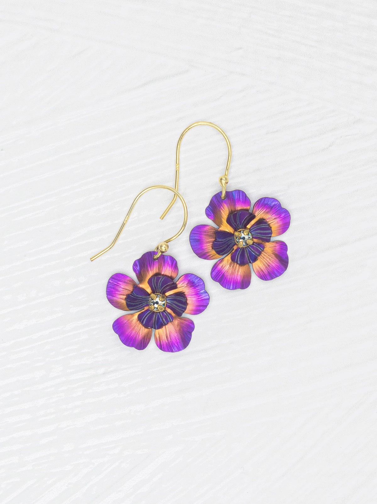 Pair of purple flower-shaped earrings on a white background