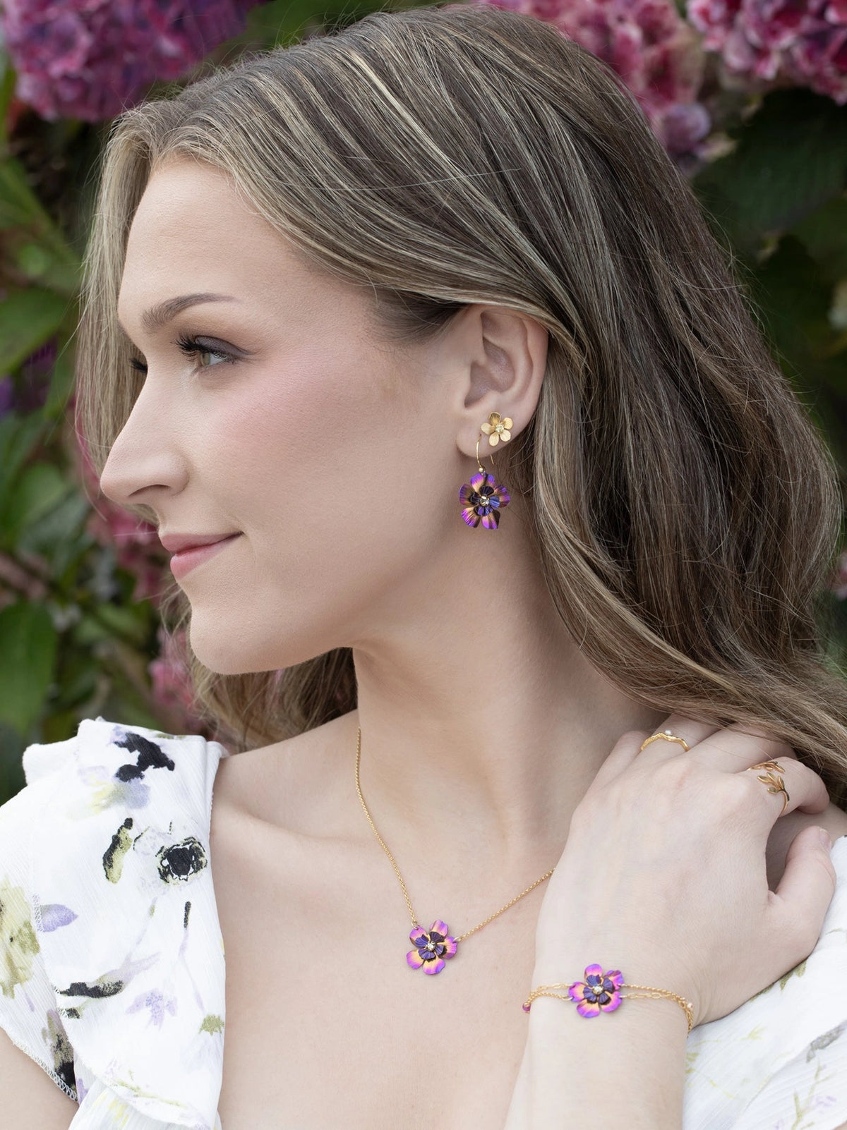 Woman wearing floral jewelry with a blurred floral background