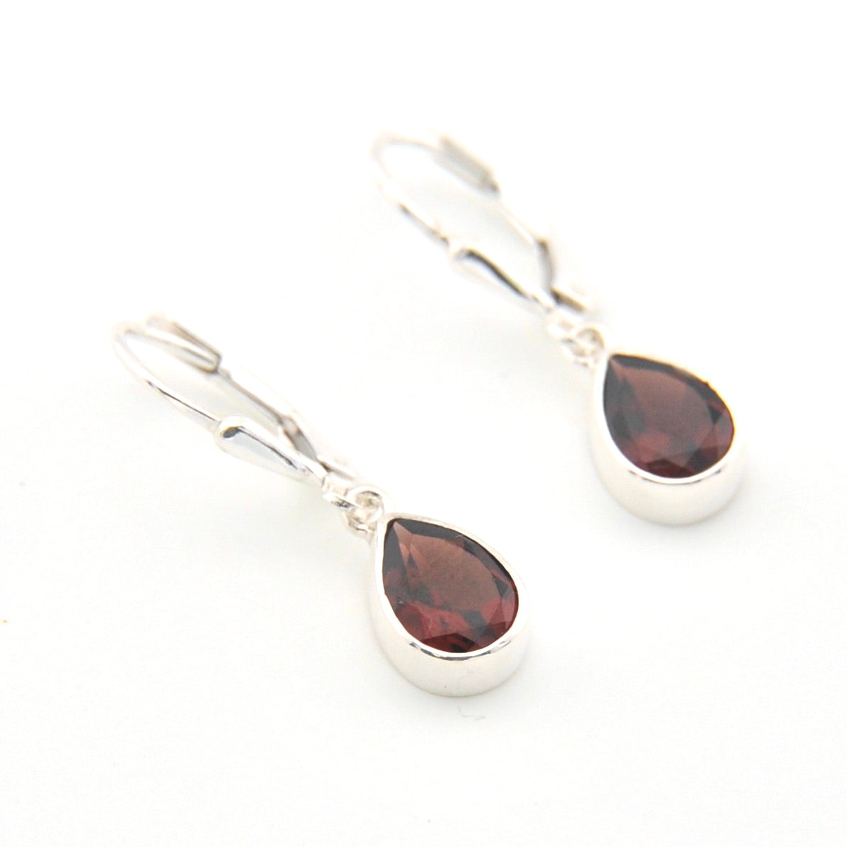 Silver earrings with teardrop-shaped gemstones on a white background