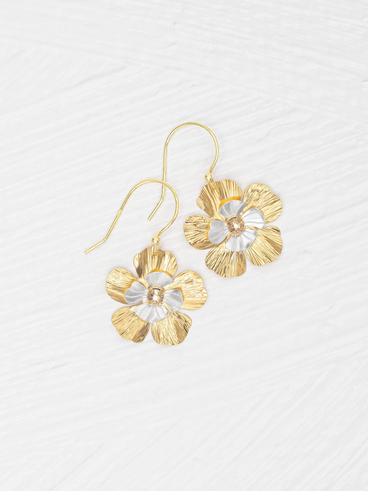 Gold flower-shaped earrings on a light gray background