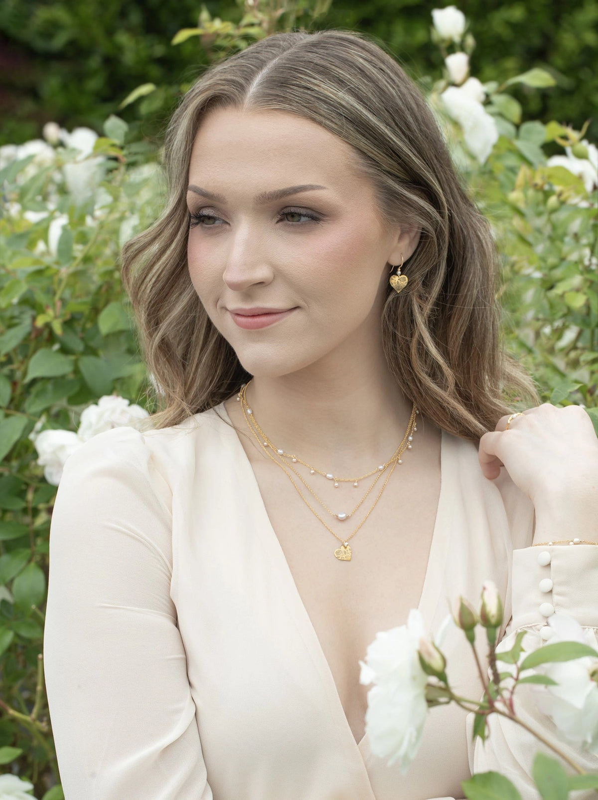 Woman wearing gold jewelry in a garden setting