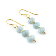 Pair of earrings with light blue beads and gold hooks on a white background