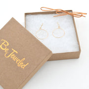 Gold earrings in a 'Be Jeweled' box on a white background