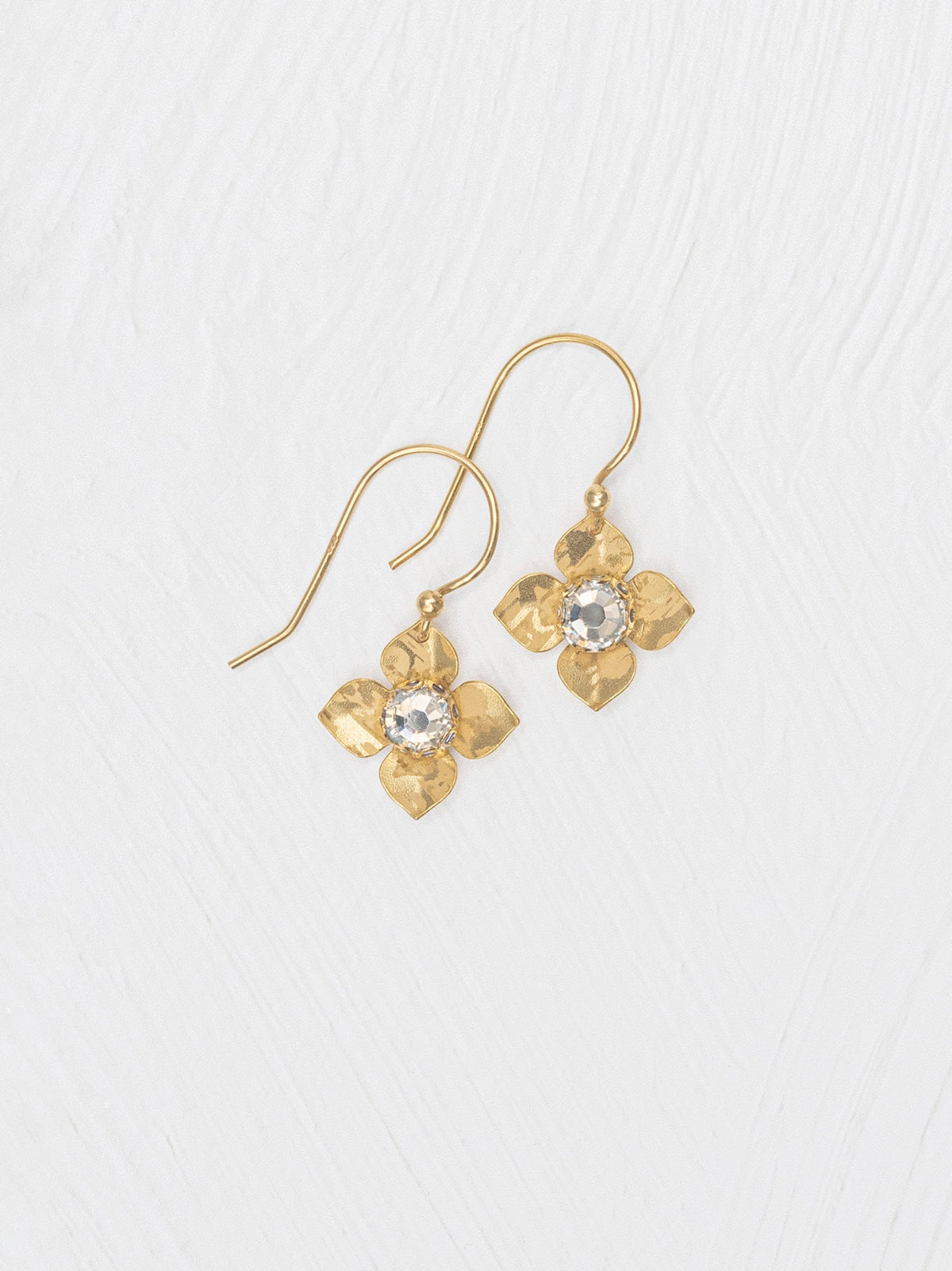 Gold flower-shaped earrings with clear gemstones on a white background