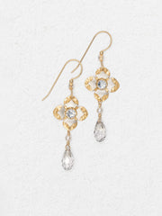 Gold earrings with floral designs and crystal-like elements on a light gray background