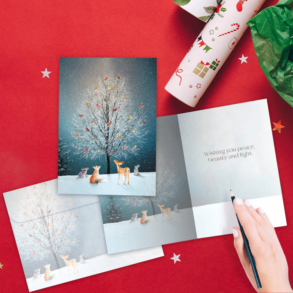 Holiday card with deer illustration on a red surface with wrapping paper and green paper.