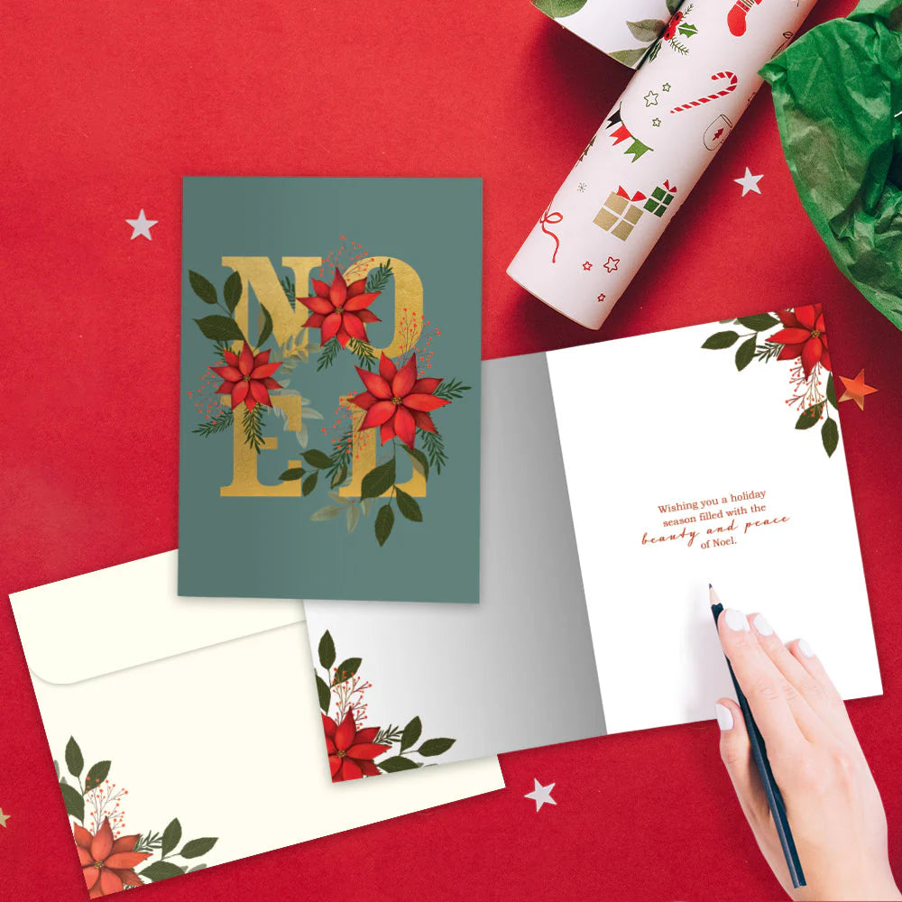 Christmas card with 'Merry' design on a red surface with wrapping paper and a pen.
