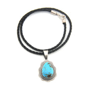 Necklace with a turquoise pendant on a black cord against a white background