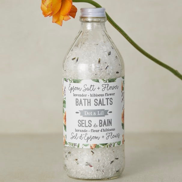 Bottle of bath salts with a floral label on a neutral background