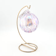 Iridescent glass ornament with a gold stand on a white background