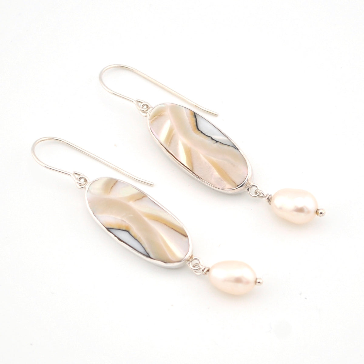 Pair of earrings with shell and pearl drop on a white background