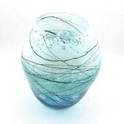 A round, bulb-shaped glass vase with a light blue tint and dark, branching line patterns resembling tree branches, set against a plain white background.