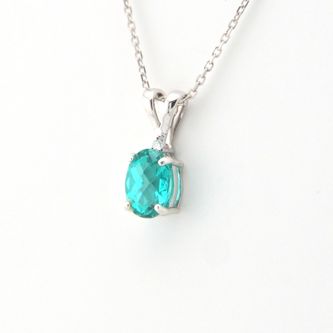 Silver necklace with a green gemstone pendant on a white background