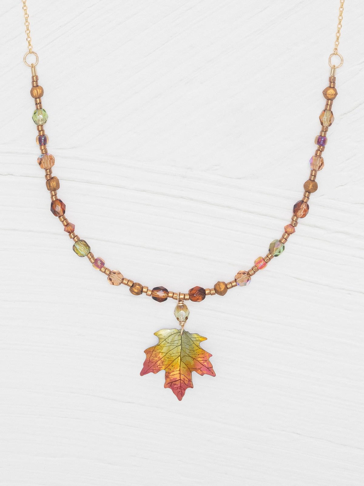 Necklace with leaf pendant and multicolored beads on a white background