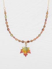 Necklace with leaf pendant and multicolored beads on a white background