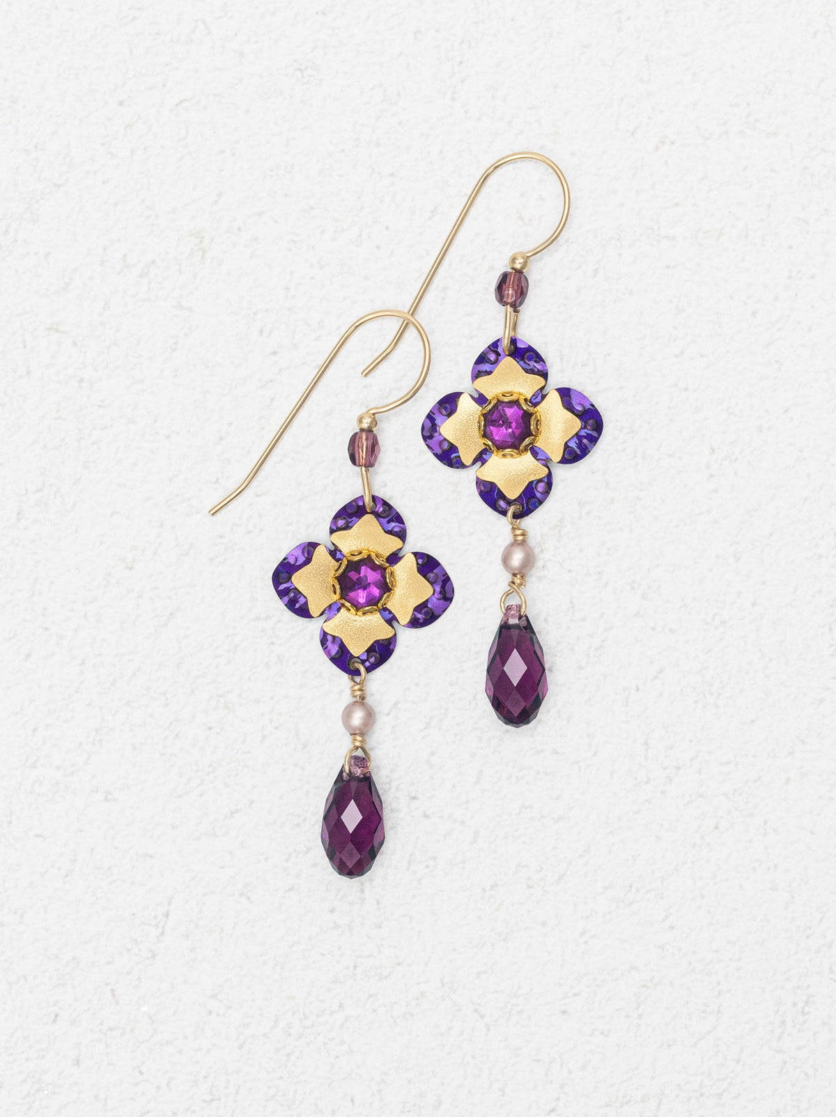 Pair of gold and purple earrings on a white background