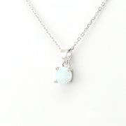 A silver necklace with a round bezel-set white opal pendant, displayed against a clean white background.