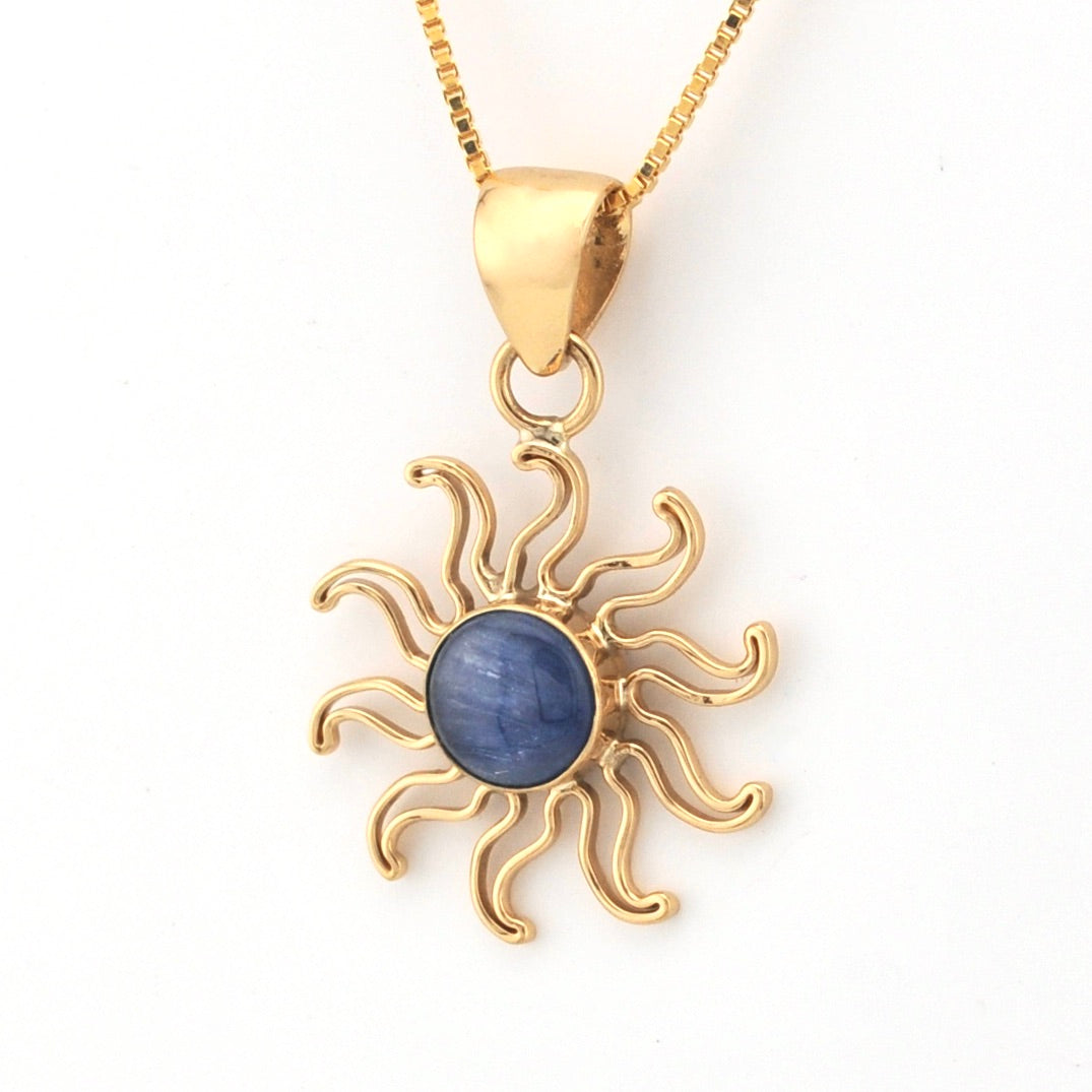 Gold sun-shaped pendant with a blue stone on a white background
