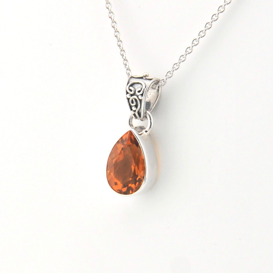 Silver necklace with a teardrop-shaped orange gemstone pendant on a white background