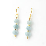 Pair of earrings with light blue beads and gold accents on a white background