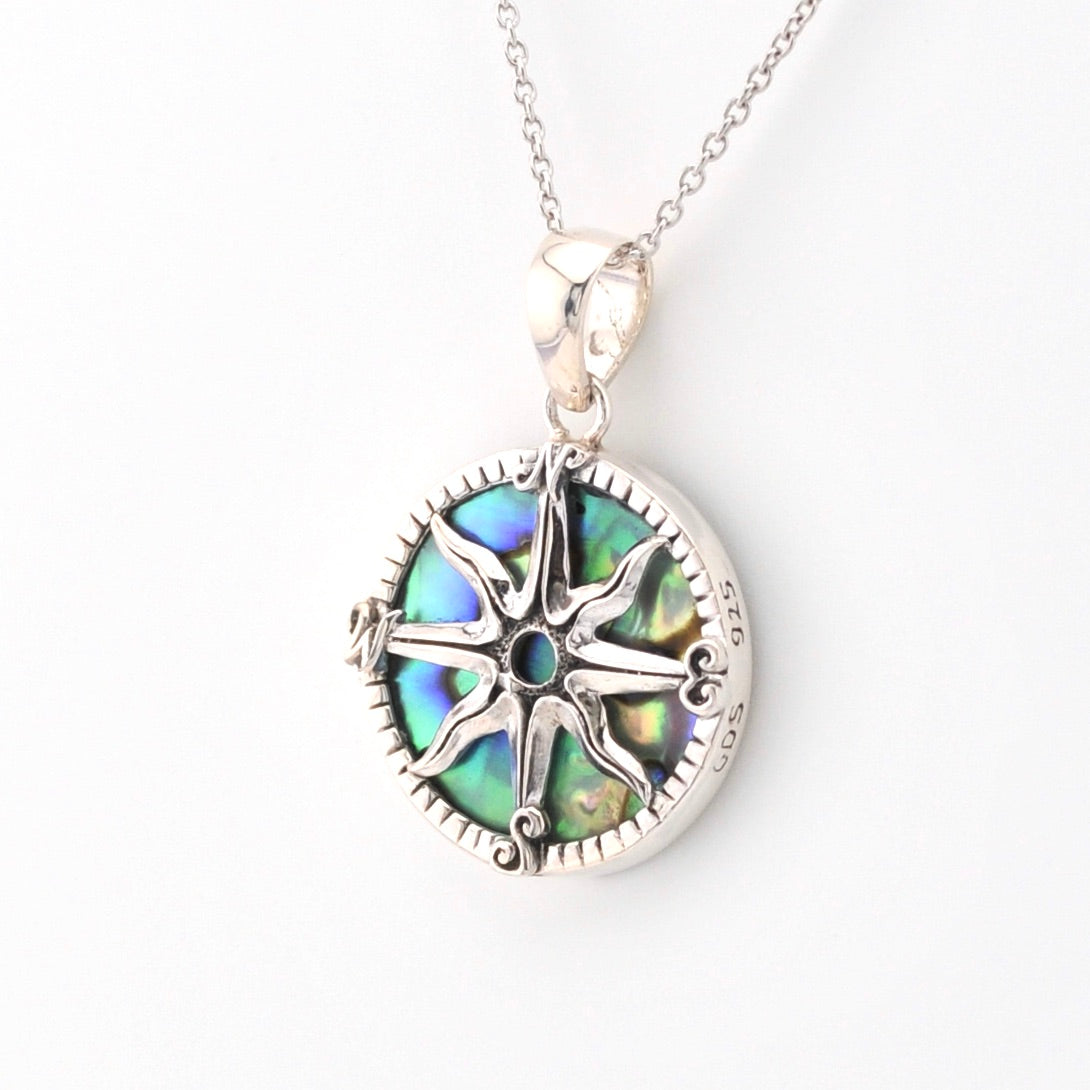 Silver necklace with a round pendant featuring a compass design on a white background
