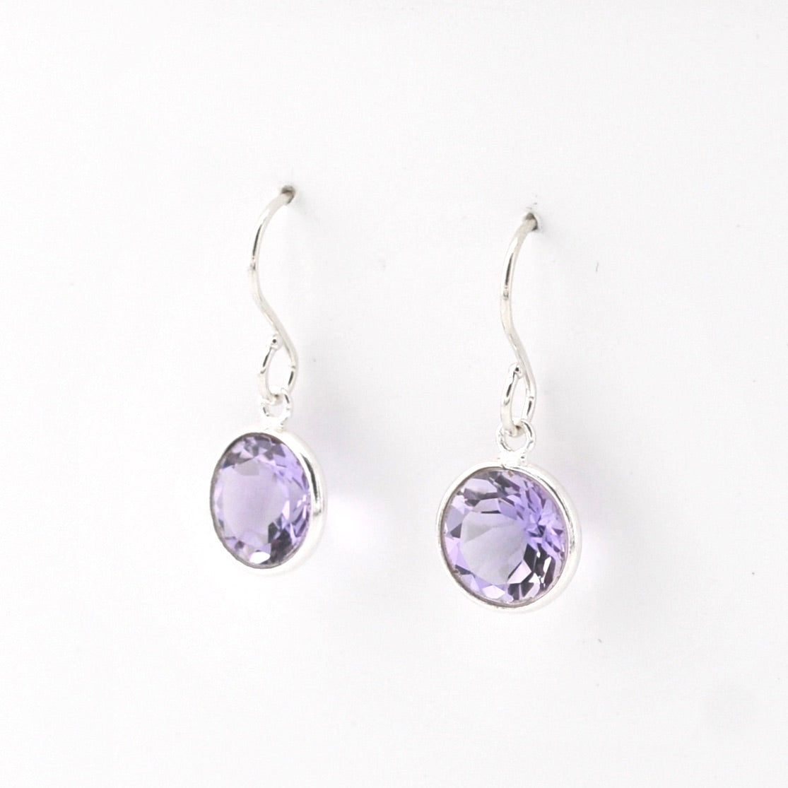Pair of silver earrings with purple gemstones on a white background