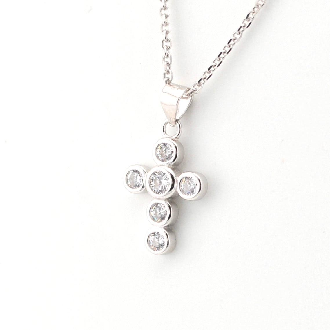 Silver cross pendant necklace with clear stones on a white background