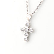 Silver cross pendant necklace with clear stones on a white background
