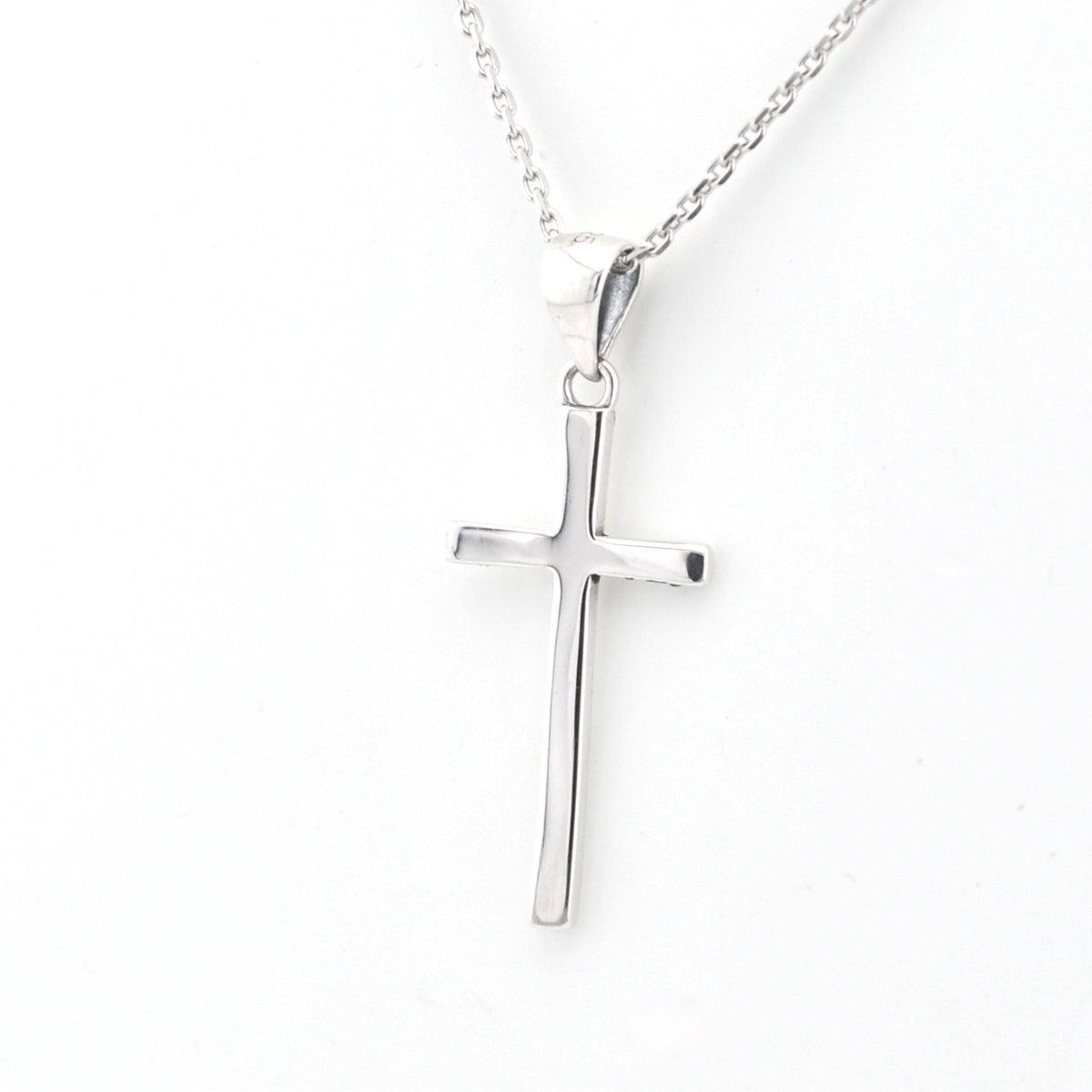 Silver cross pendant on a chain against a white background