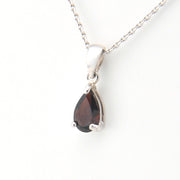 Teardrop-shaped gemstone pendant on a silver chain against a white background