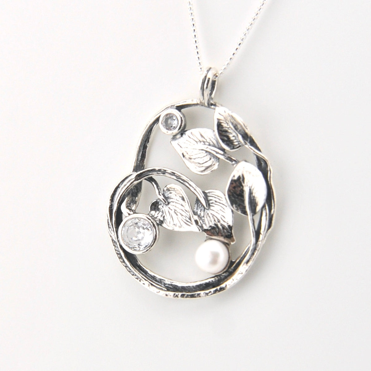 Silver pendant with floral design and pearls on a white background