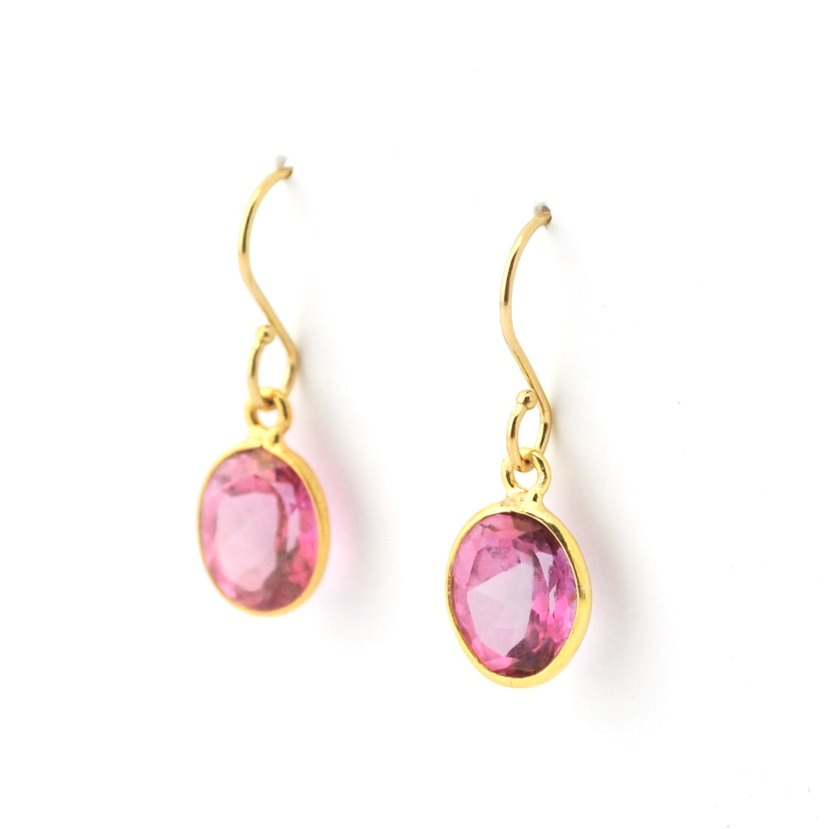 Gold earrings with pink gemstones on a white background
