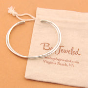 Silver bracelet on a Be Jeweled branded pouch against a beige background