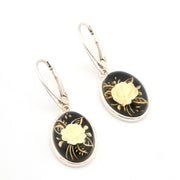 Pair of earrings with black and gold floral designs on a white background