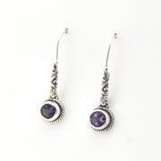 Silver earrings with purple gemstones on a white background