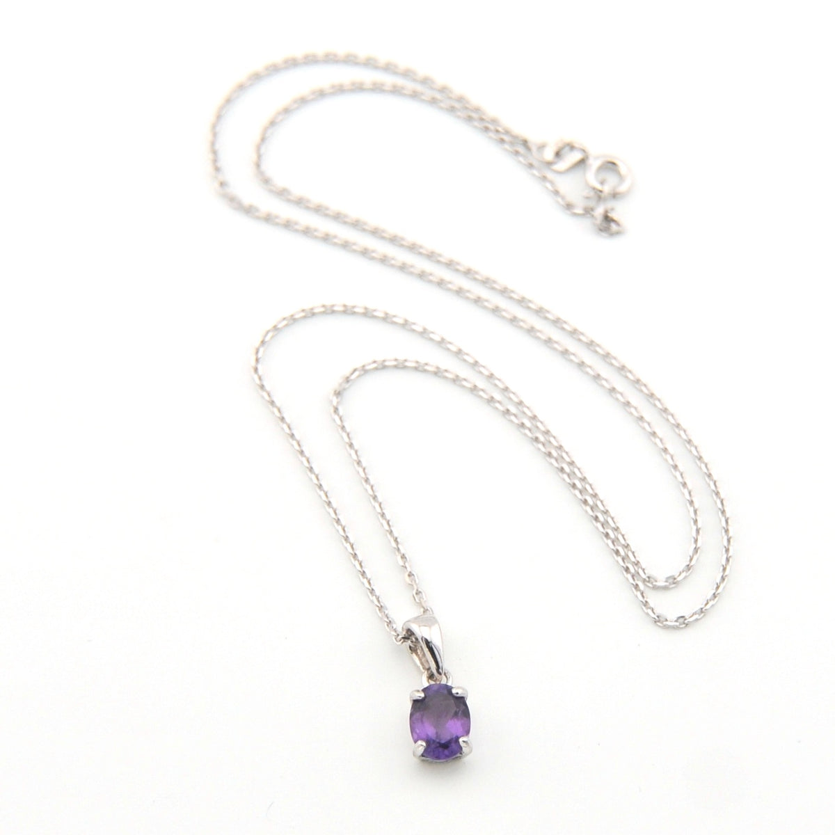 Silver necklace with a purple gemstone pendant on a white background