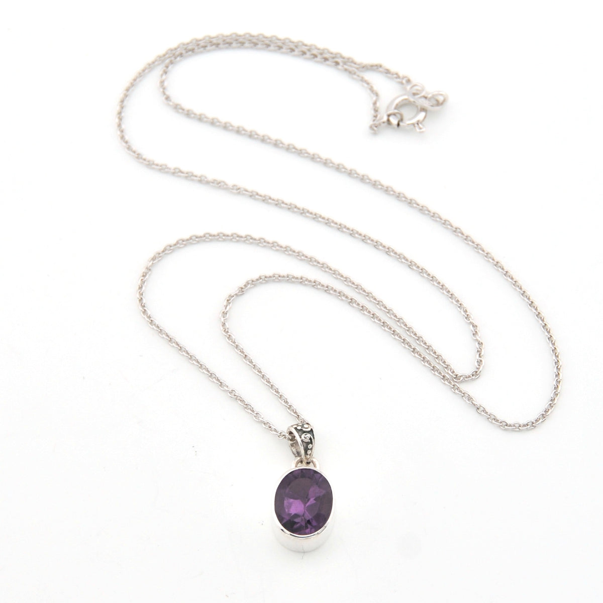 Silver necklace with a purple pendant on a white background