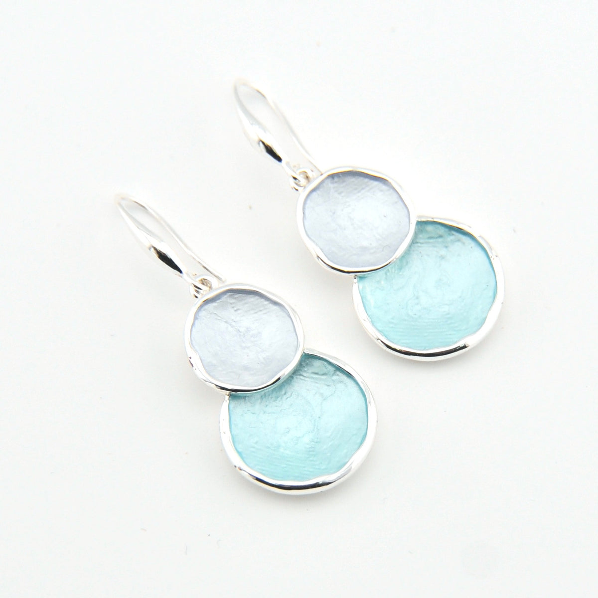 Pair of earrings with light blue circular stones on a white background