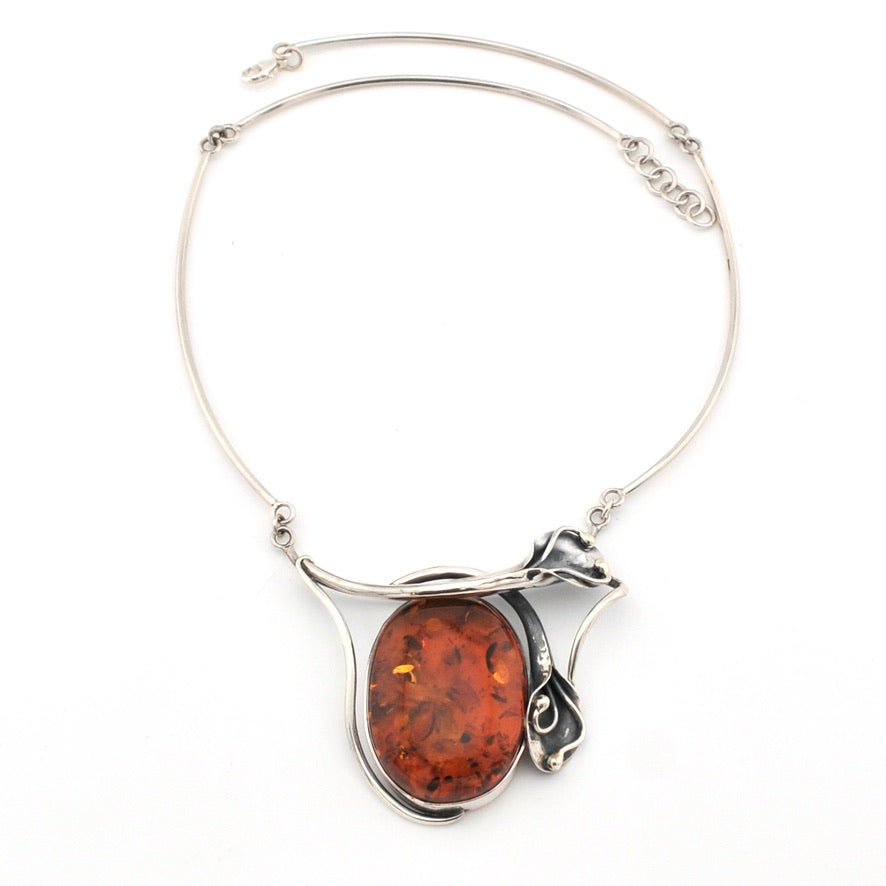 Silver necklace with a large amber pendant on a white background