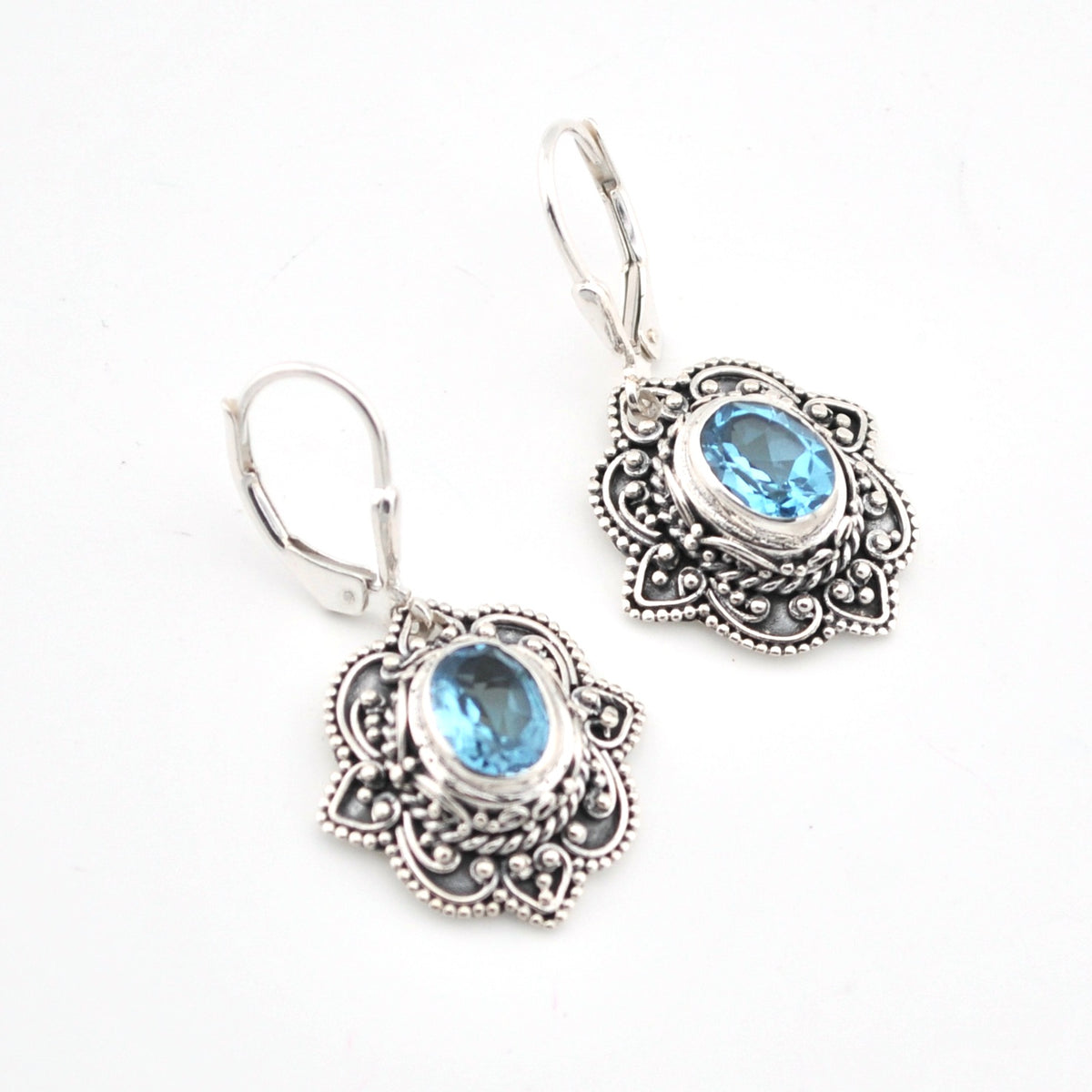 Silver earrings with blue gemstones on a white background