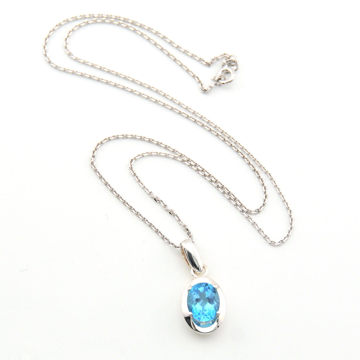 Silver necklace with a blue gemstone pendant on a white background