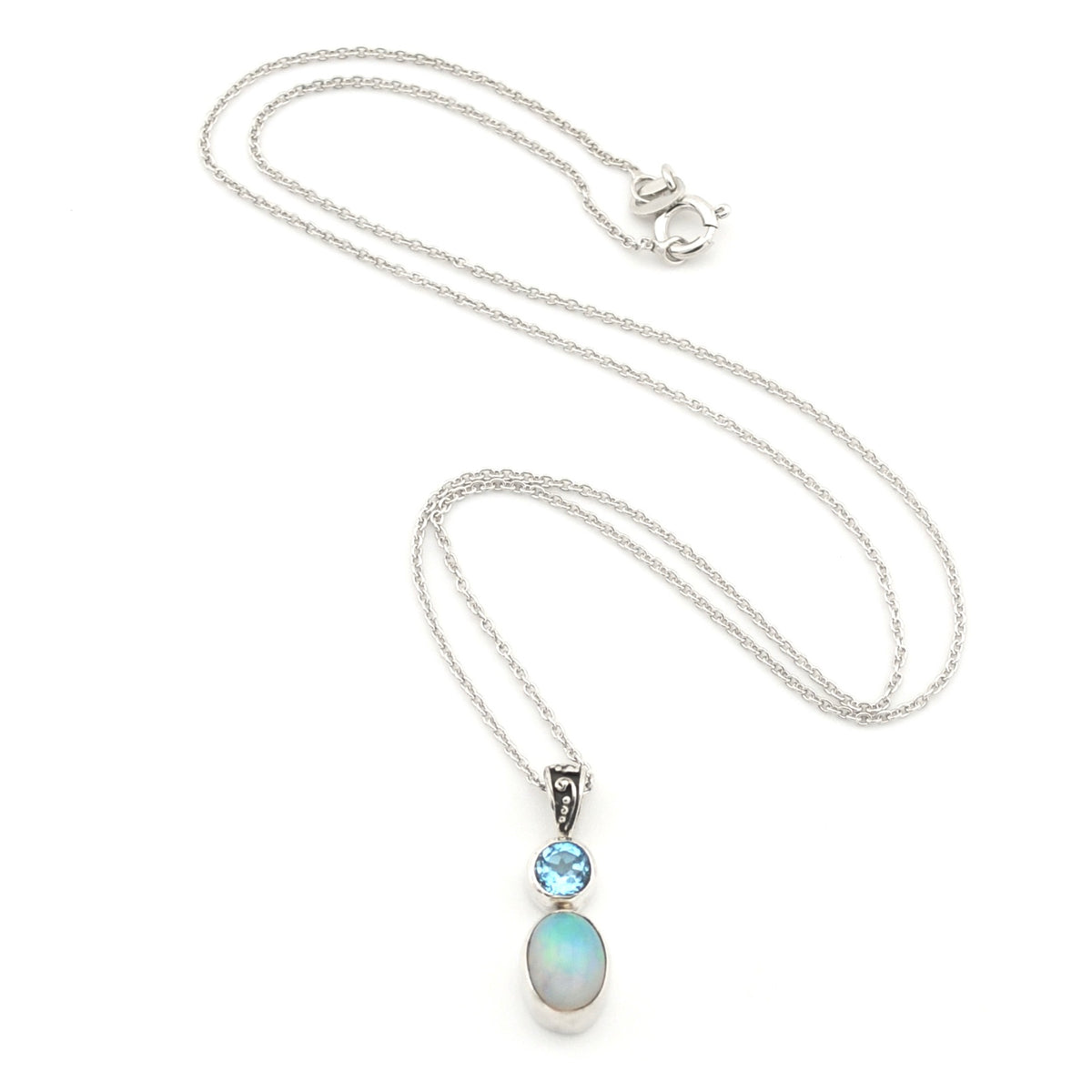 A silver necklace featuring a pendant with a small round light blue gemstone and an oval iridescent opal stone, displayed on a clean white background.
