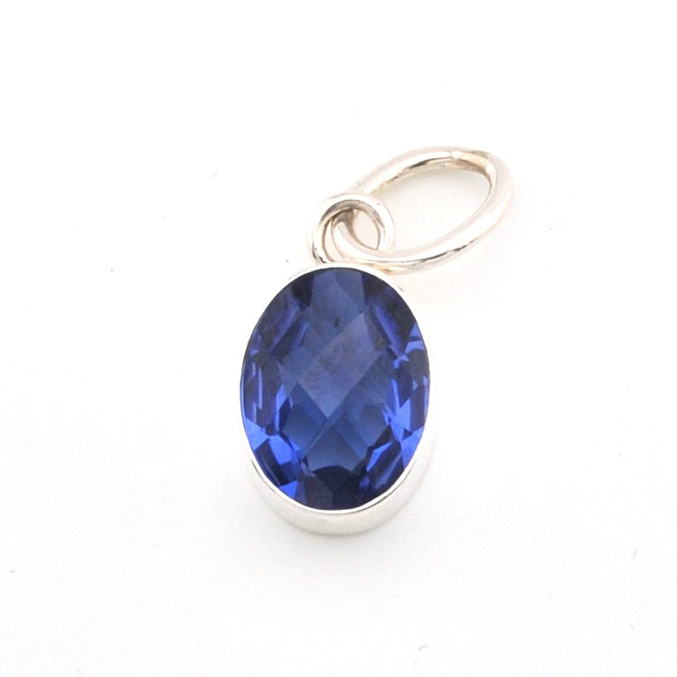 Silver pendant with a blue gemstone on a white background